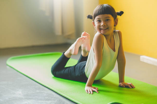 Image of Asian cute girl Practicing On Yoga Mat at living room.